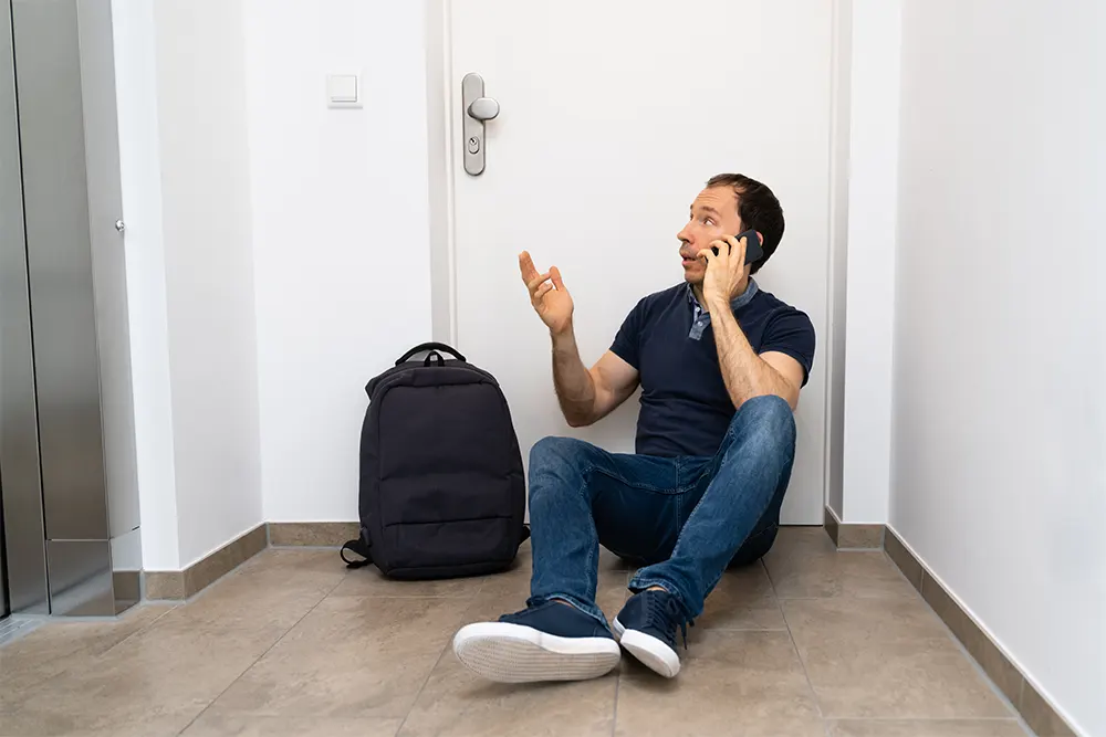 A desperate man leans against a locked door and talks on the phone