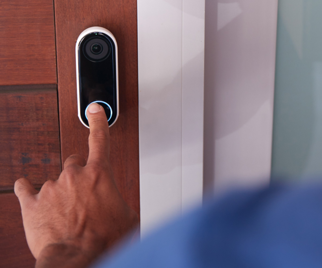 A man pressing the video doorbell installed at the door of a house
