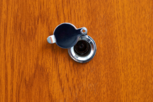 A peephole with cover placed in a wooden door